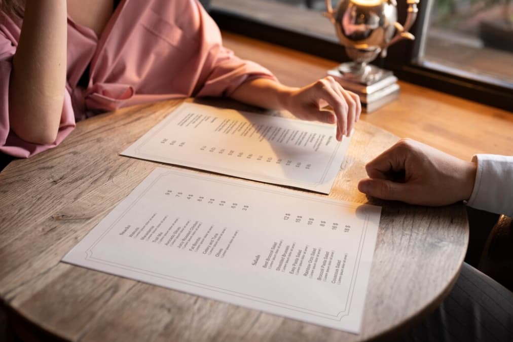 Two people examining a menu on a rustic wooden table